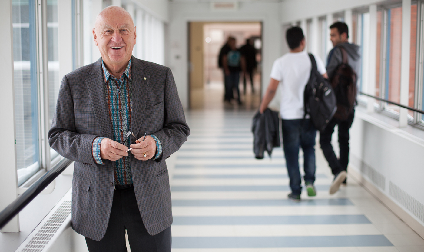 JR Shaw stands in pedway on NAIT main campus holding a pair of glasses.