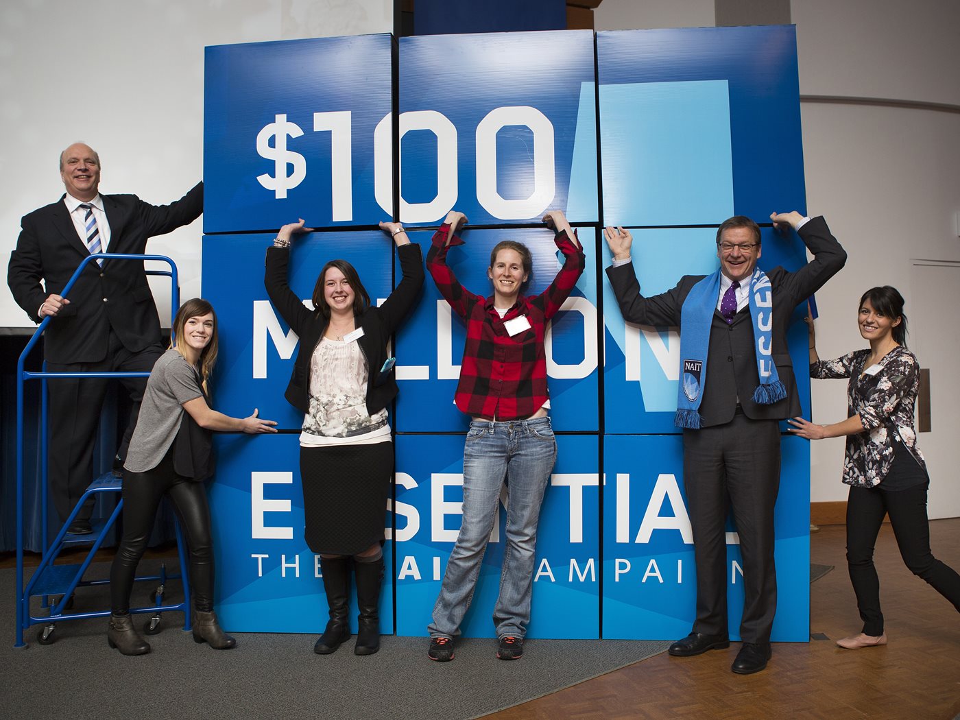 Brent Hesje, a group of students and then-president and CEO Dr. Glenn Feltham stand in front of large building blocks.