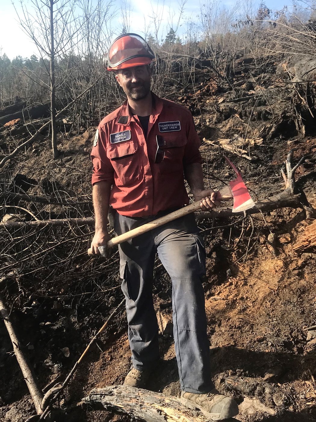Harold Larson stands with an axe at a wildland fire site.