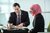 Man in a tie speaks to female student wearing a pink hijab