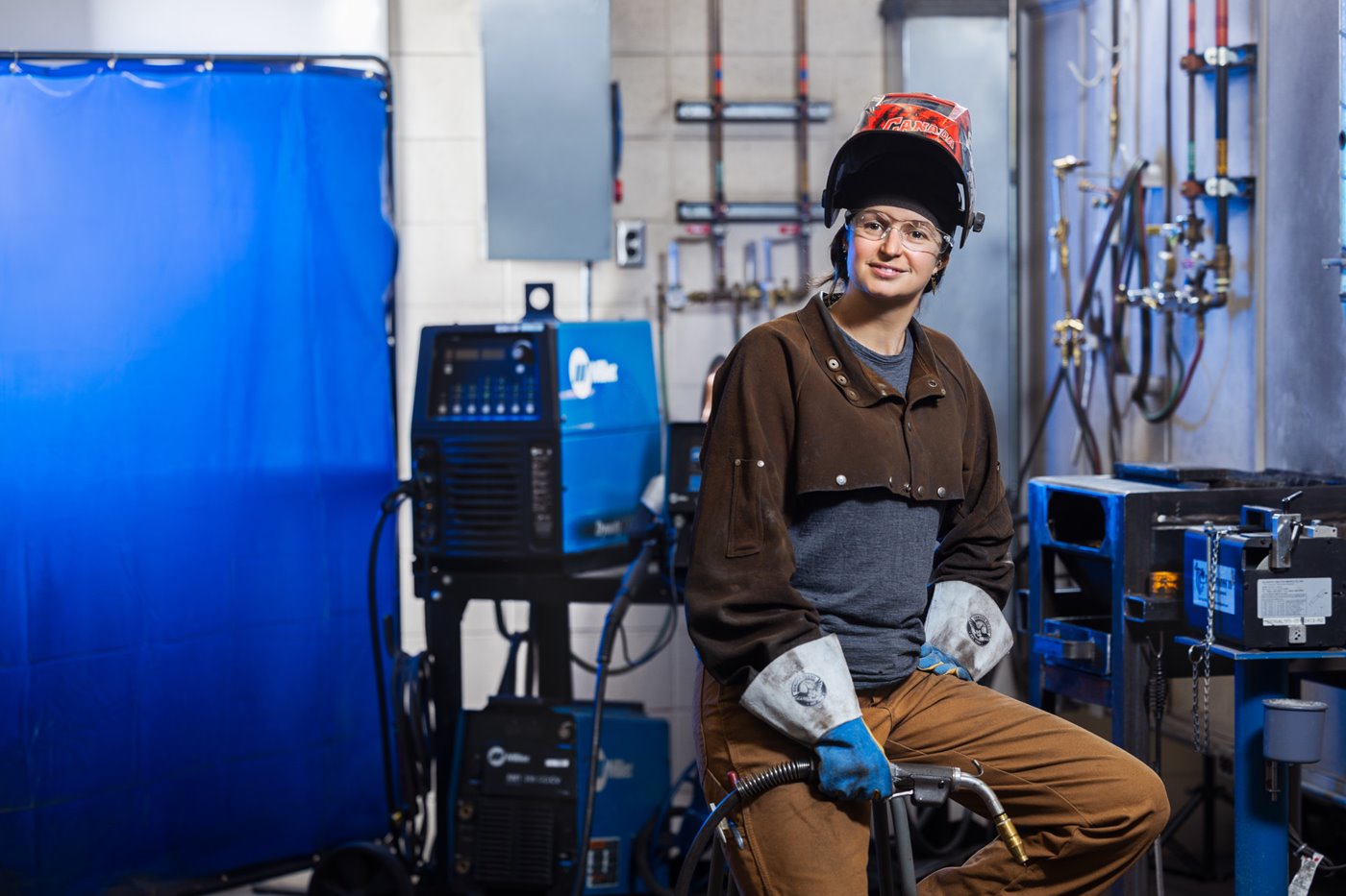 female welder poses in front of welding equipment