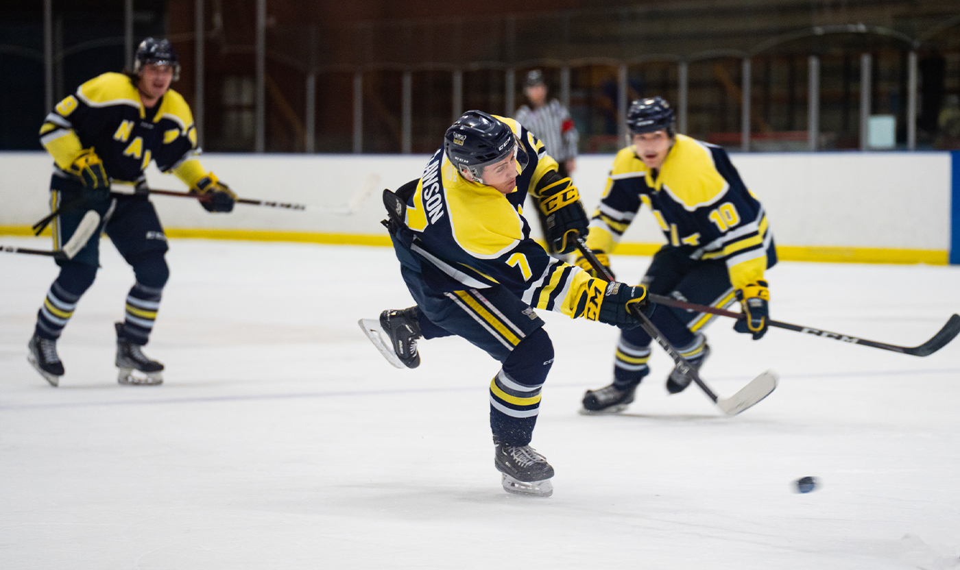 Brandon Lawson firing a slapshot against the away team with his defensive players skating behind