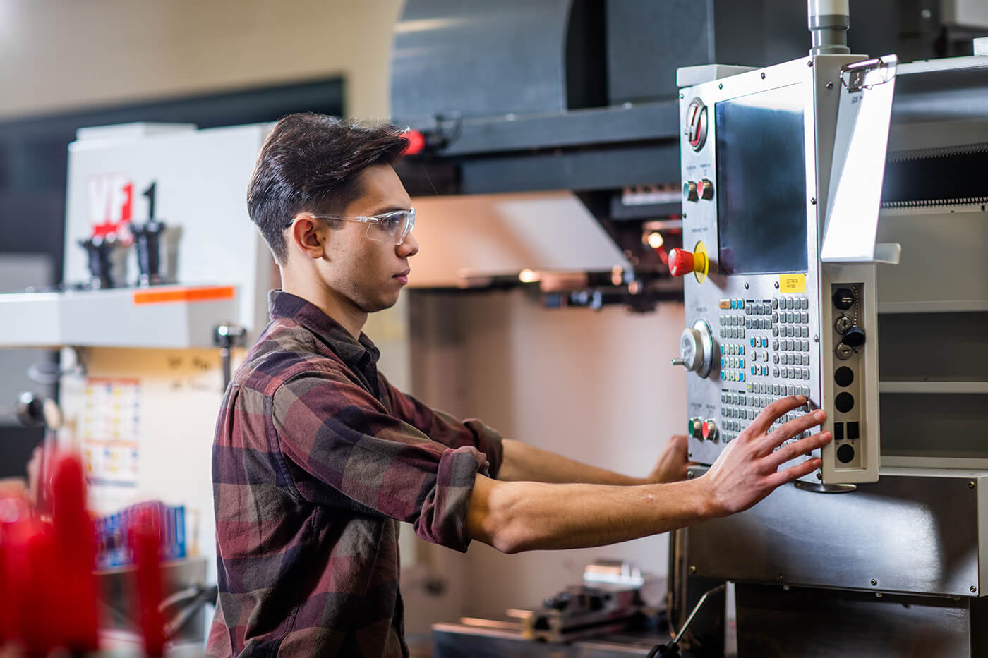 Machinist student wearing eye protection works in a workshop