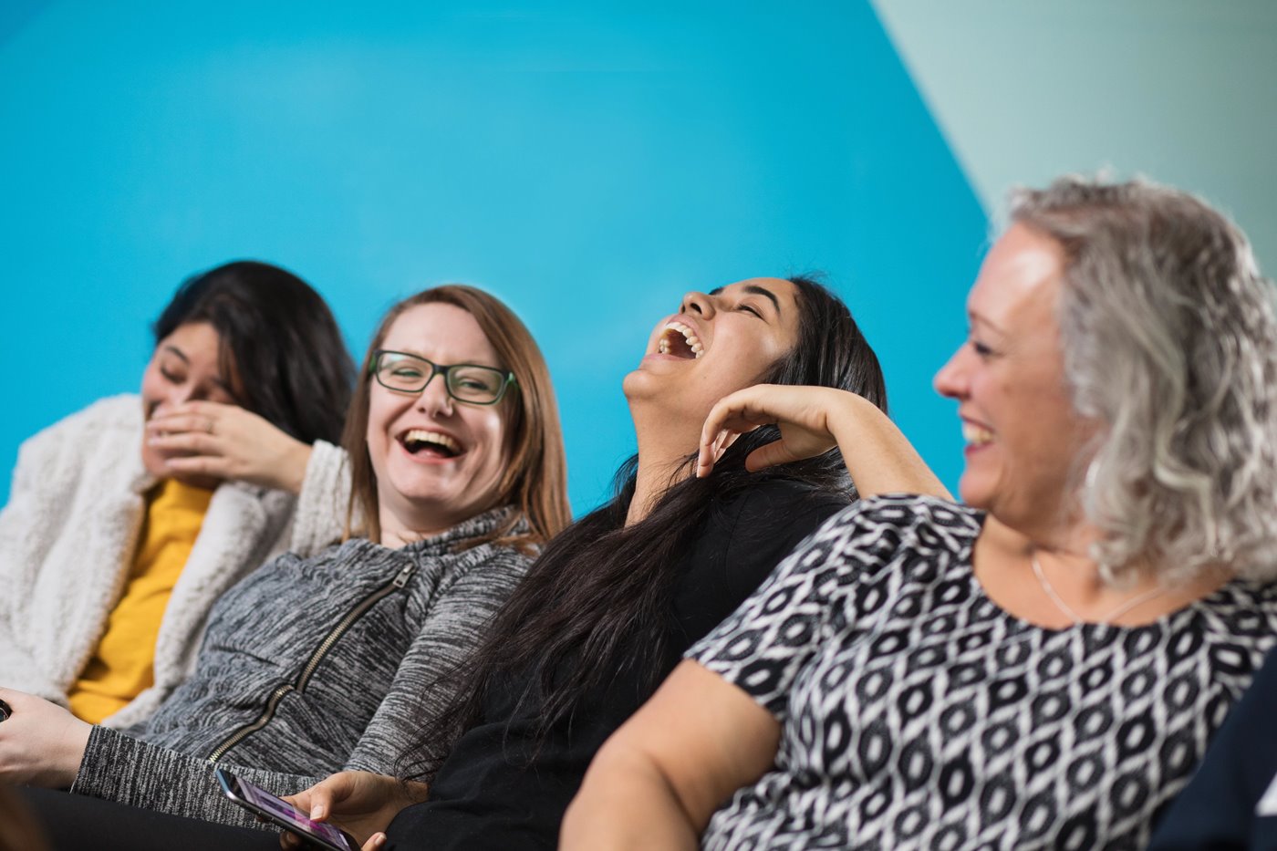 Four women sitting together and laughing