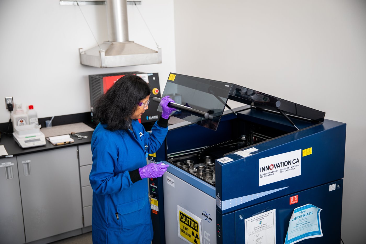 a scientist in a blue lab coat working at a machine