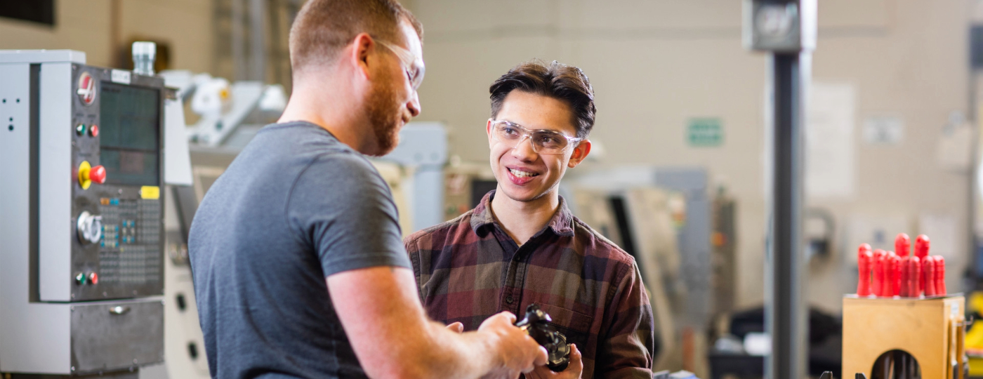instructor helping machining student in a lab